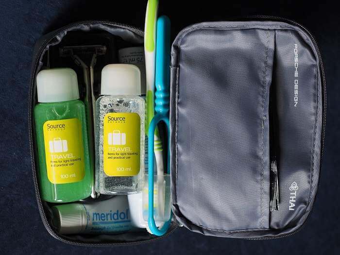 essential travel toiletries for travel including toothbrash shampoo and conditioner in black toiletry bag