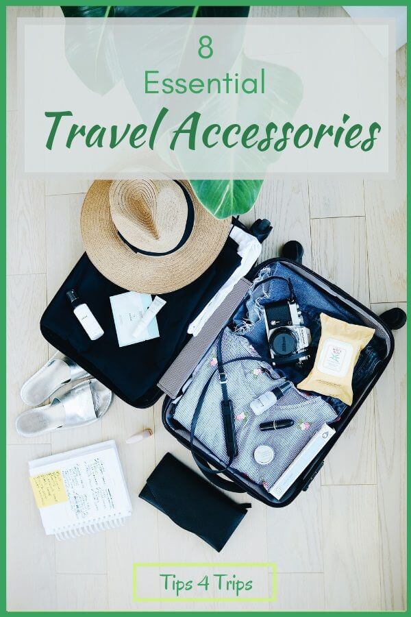 A suitcase filled with travel essentials including hat, camera, pen, book, flat shoes and shirt