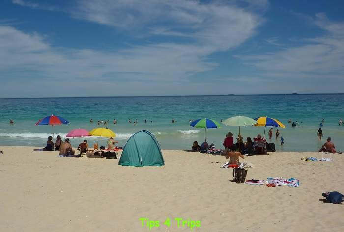 People sitting at the beach under shade of umbrellas