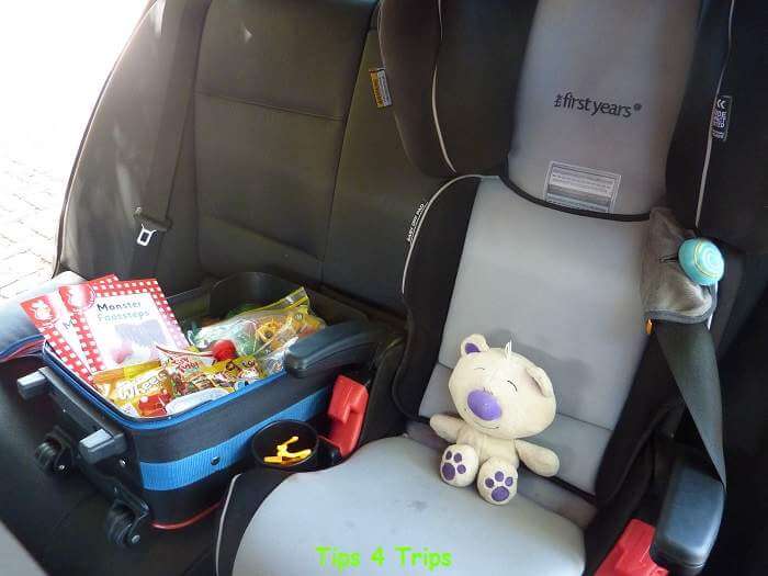 Toys and snacks in bag next to toddler car seat for family road trips