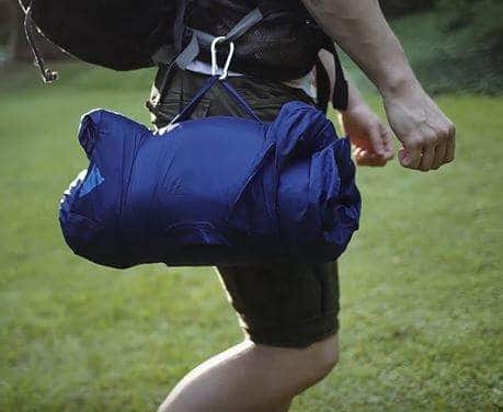 A backpacker carrying his pillow with the aid of a Sleep Keeper