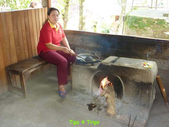 Balinese lady sitting as she roasts Luwak coffee over an open flame
