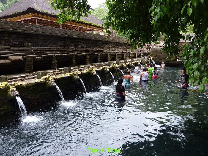 people bathing under the row of Tirta Empul holy springs