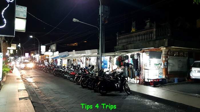 A Bali street at night with motorbikes and market stalls