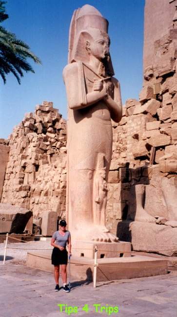 Woman standing in front of very tall statue in Karnac Temple in Egypt