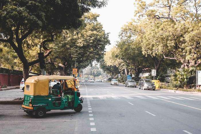 green and yellow tuktuk pulling out onto road in India