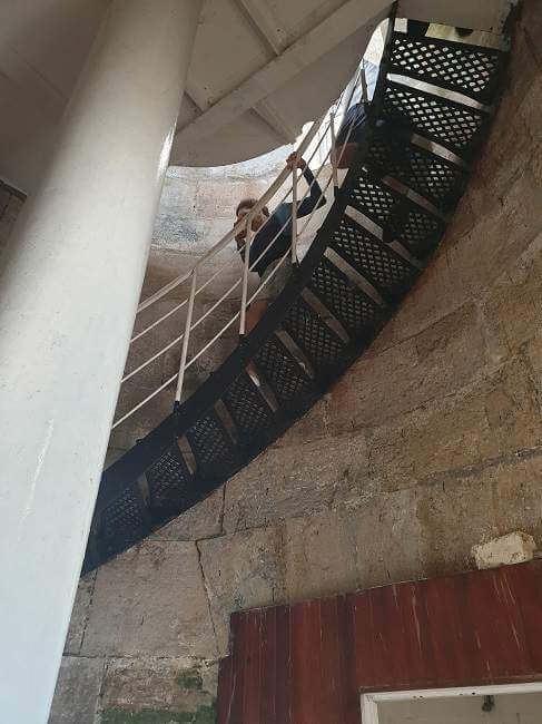 person walking down circular staircase inside the lighthouse