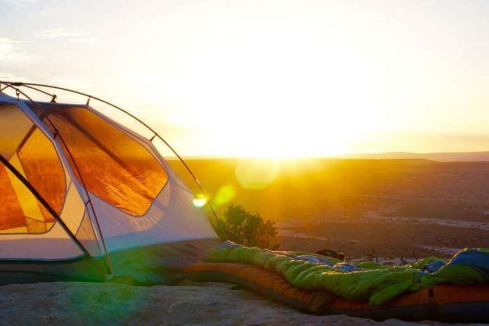 sleeping bag next to tent at sunrise