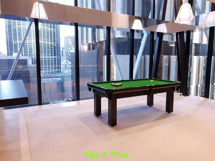 A pool table in front of large floor to ceiling windows