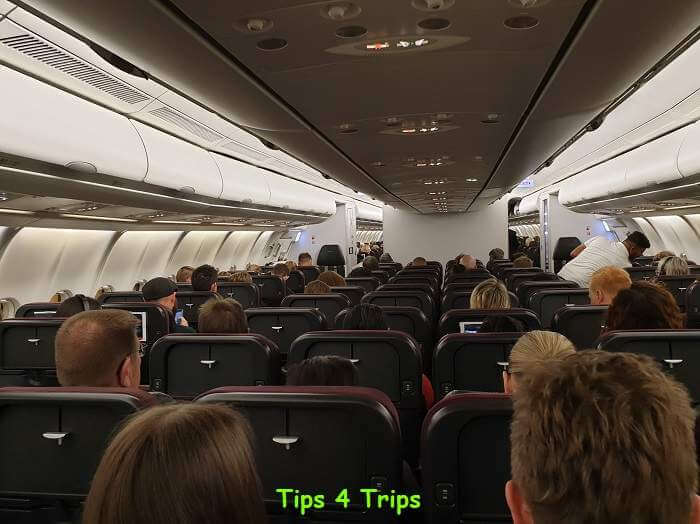 rows of people sitting on board in economy class on a Qantas A330