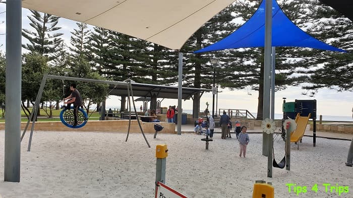 Kids playing in playground on Busselton foreshore, people BBQing in background