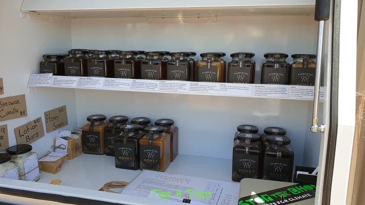 two white shelves filled with jars of different flavoured honey