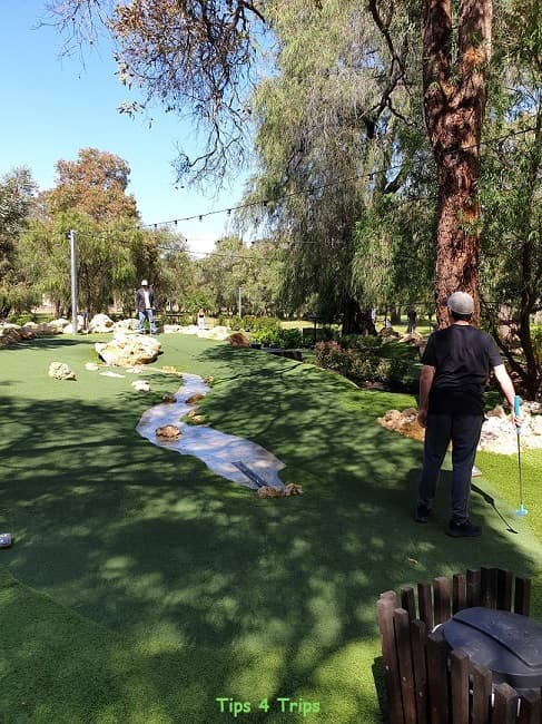 father and son playing minigolf at a hole with a stream as an obstacle at Busselton Par 3 course